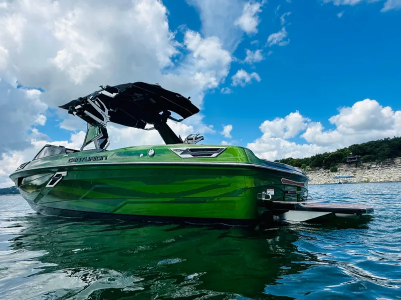 Slide: The Image of 2021 Centurion Ri245 boat on water, vibrant green, under blue sky with clouds. - 8
