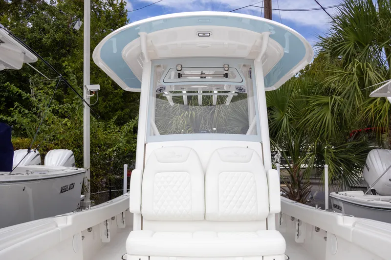 Slide: The Image of 2025 Regulator 26XO boat with white seating and canopy, surrounded by greenery. - 14