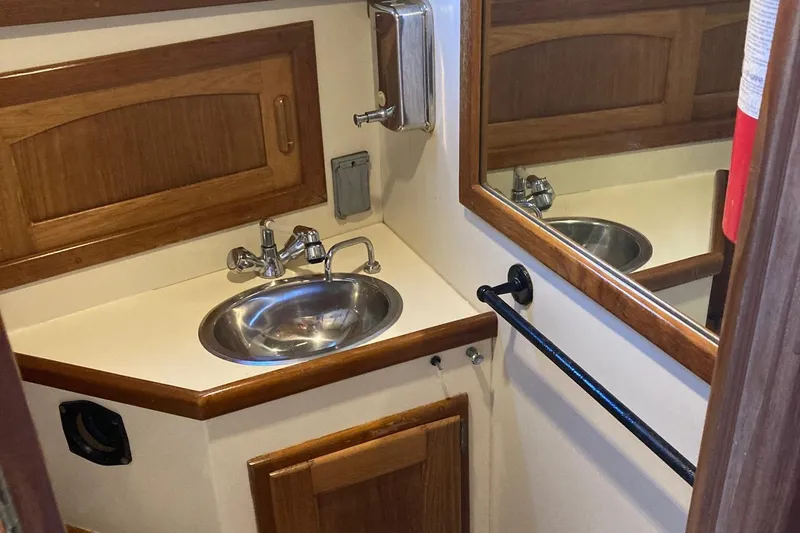 Slide: The Image of 1992 Pacific Seacraft 37 Cutter bathroom with sink, mirror, and wooden cabinetry. - 16