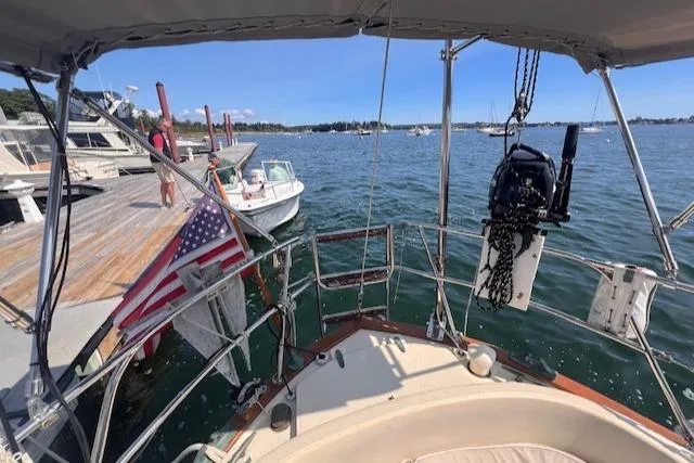 Slide: The Image of 1992 Pacific Seacraft 37 Cutter docked, with American flag, overlooking calm marina waters. - 19