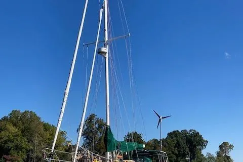 Slide: The Image of 1992 Pacific Seacraft 37 Cutter sailboat with green cover, docked under clear blue sky. - 36