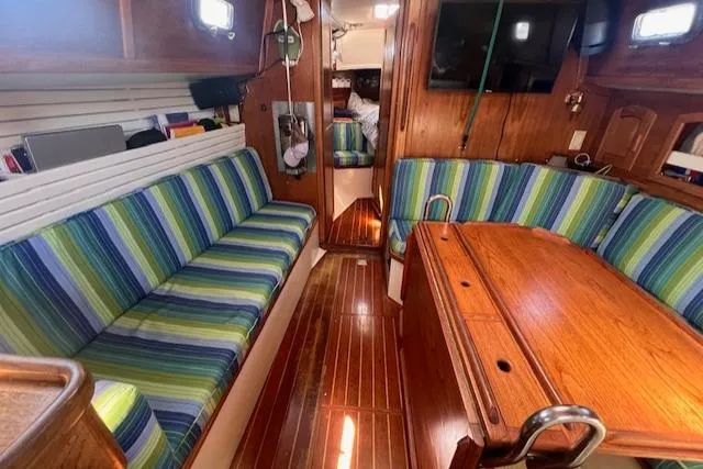 Slide: The Image of Interior of 1992 Pacific Seacraft 37 Cutter with striped seating and wooden table. - 8