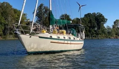 The Image of 1992 Pacific Seacraft 37 Cutter sailboat anchored on a calm lake with trees in the background. - 0