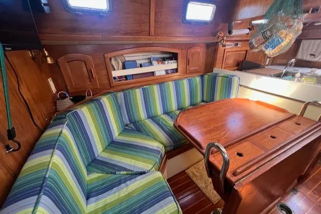 Slide: The Image of Interior of 1992 Pacific Seacraft 37 Cutter with striped seating and wooden table. - 2
