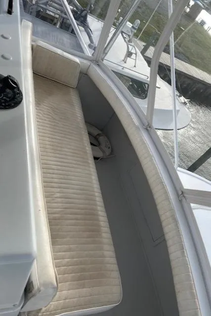 Slide: The Image of 1985 Bertram 38 Convertible boat interior with cushioned seating and window view. - 23