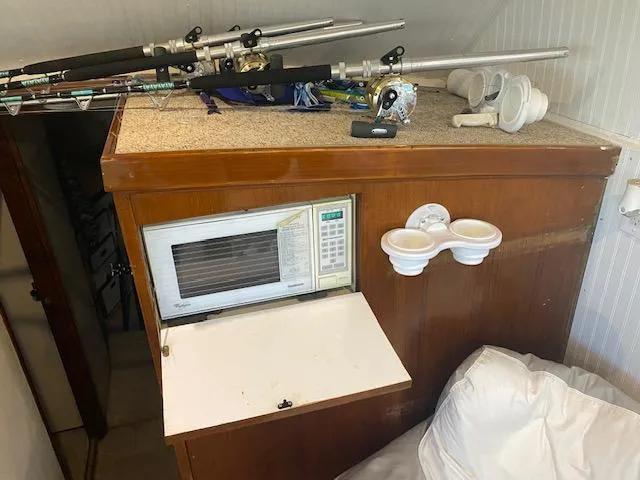 Slide: The Image of 1985 Bertram 38 Convertible interior with fishing rods, microwave, and cup holders. - 31