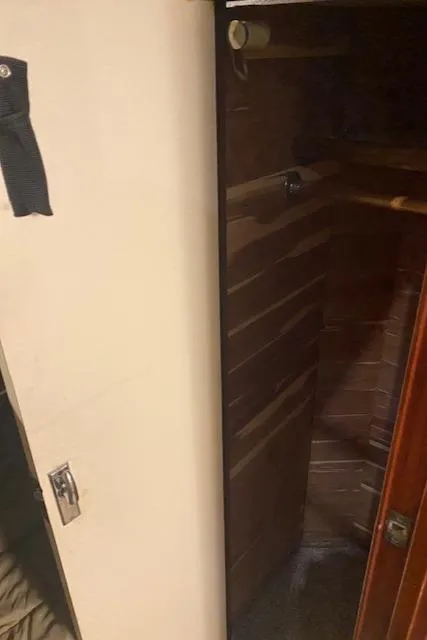 Slide: The Image of Interior view of 1985 Bertram 38 Convertible, featuring wooden paneling and storage space. - 38