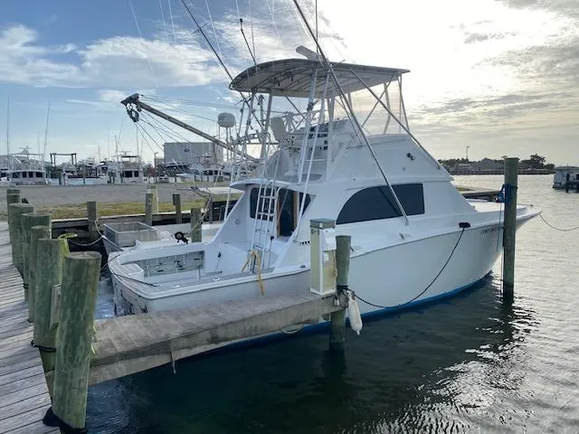 Slide: The Image of 1985 Bertram 38 Convertible yacht docked at marina under cloudy sky. - 4