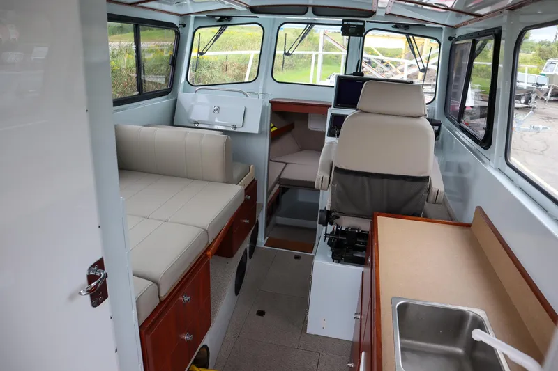 Slide: The Image of Interior of 2024 Hewescraft 270 Pacific Explorer, featuring seating and a compact kitchen area. - 10