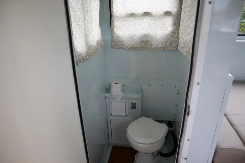 Slide: The Image of 2024 Hewescraft 270 Pacific Explorer bathroom interior with toilet and window curtain. - 18