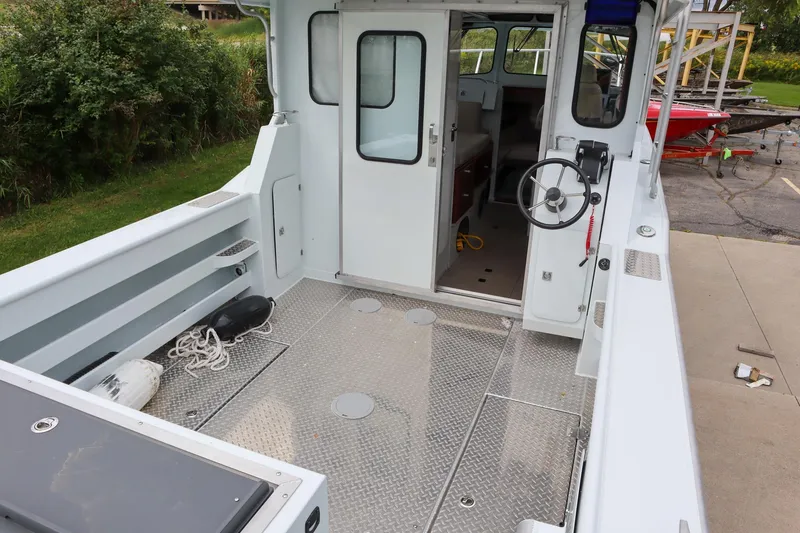 Slide: The Image of 2024 Hewescraft 270 Pacific Explorer boat interior with steering wheel and open cabin door. - 4