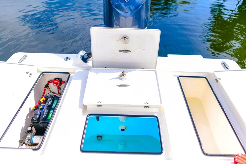 Slide: The Image of 2022 Hewes Redfisher 21 boat compartments with battery and storage, on calm water. - 21