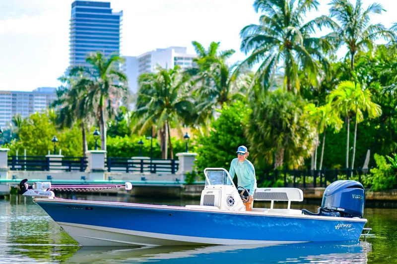 Slide: The Image of 2022 Hewes Redfisher 21 boat on water, with palm trees and cityscape in background. - 4