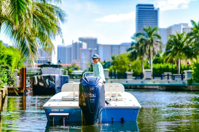 Slide: The Image of 2022 Hewes Redfisher 21 boat on a scenic waterway with city skyline and palm trees. - 8