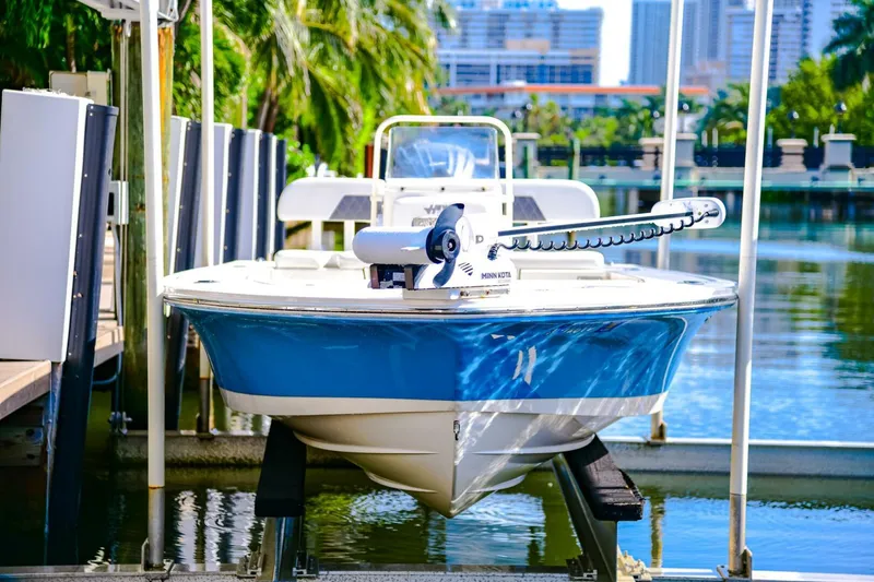 Slide: The Image of 2022 Hewes Redfisher 21 boat docked, blue and white hull, urban waterfront background. - 9