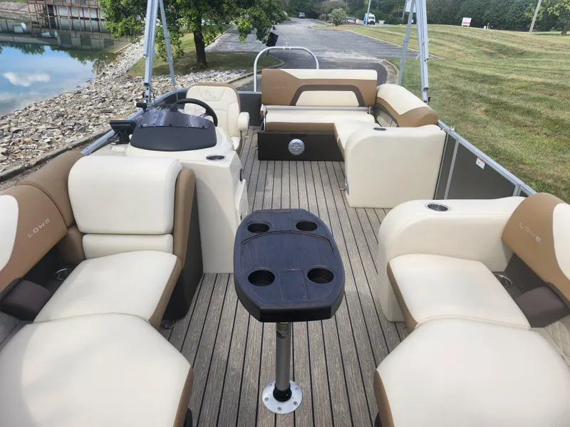 Slide: The Image of 2022 Lowe SS 210 CL pontoon boat with beige seating and central table on a wooden deck. - 10