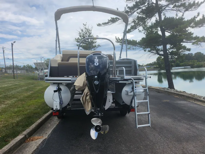 Slide: The Image of 2022 Lowe SS 210 CL pontoon boat with 150 HP engine, parked near a lake. - 2