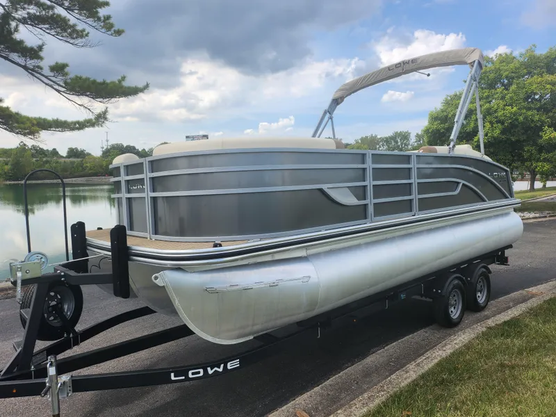 Slide: The Image of 2022 Lowe SS 210 CL pontoon boat on trailer by a lake. - 8