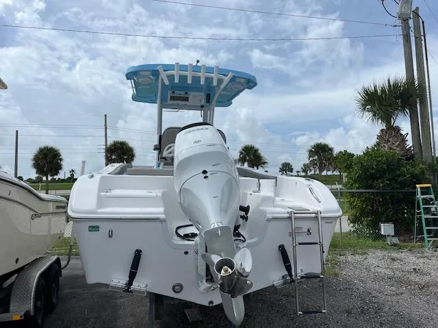 Slide: The Image of 2025 Sea Pro 242 DLX boat with outboard motor, parked outdoors. - 3