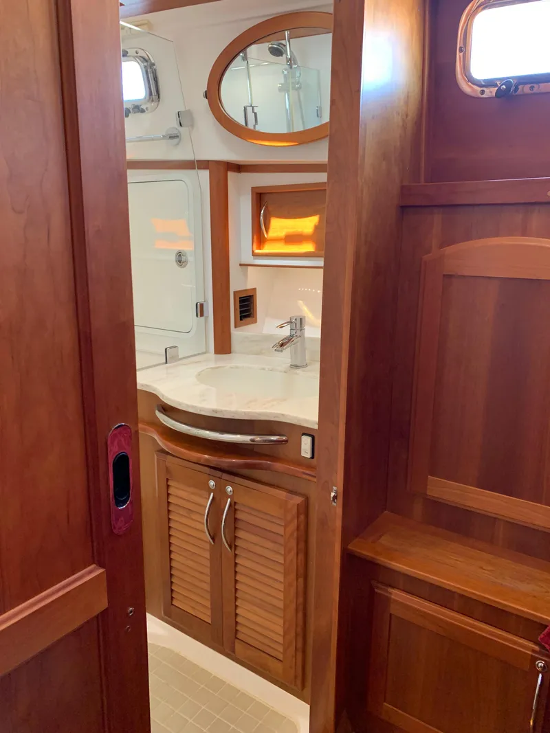 Slide: The Image of 2014 Sabre 48 Salon Express bathroom with wooden cabinetry and oval mirror. - 10
