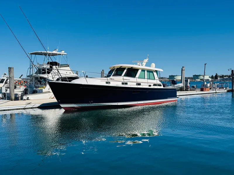Slide: The Image of 2014 Sabre 48 Salon Express yacht docked in a marina under clear blue skies. - 2