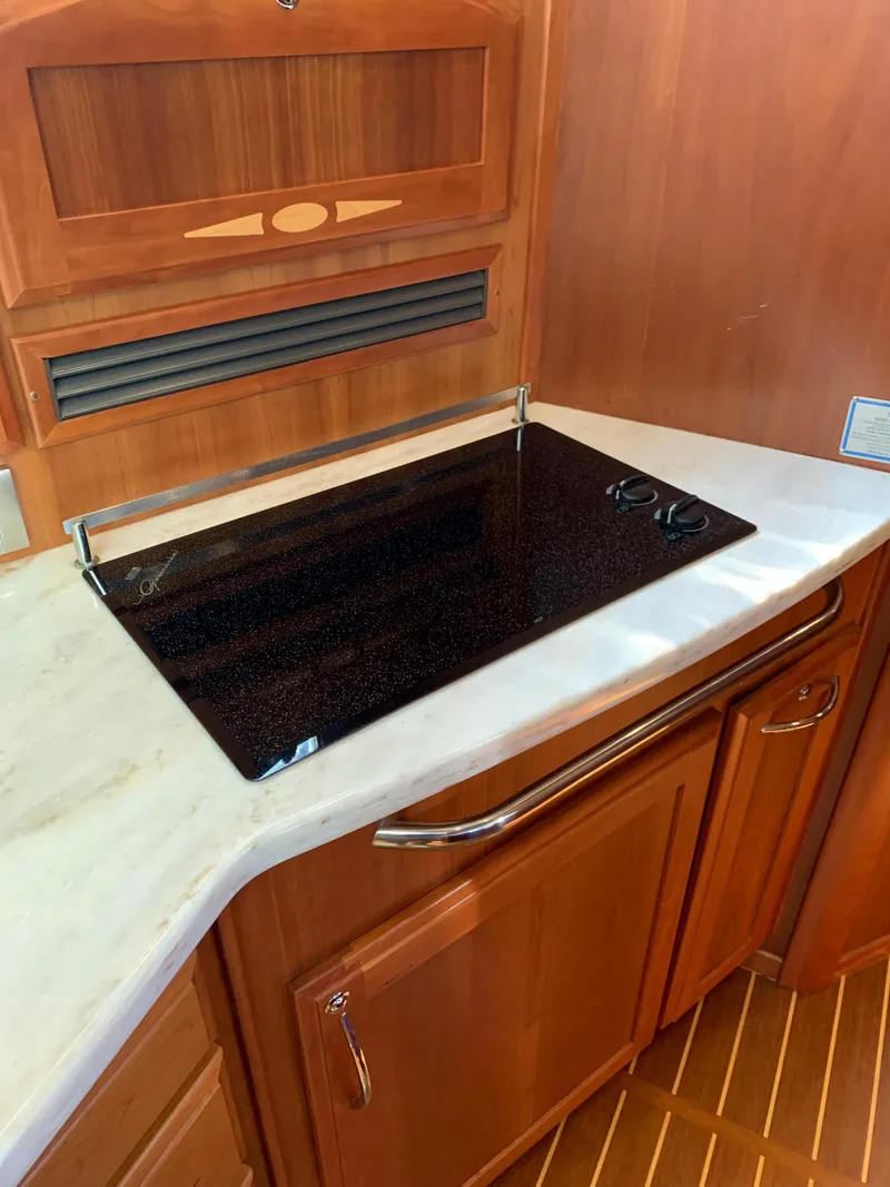 Slide: The Image of 2014 Sabre 48 Salon Express kitchen with sleek stovetop and wooden cabinetry. - 27