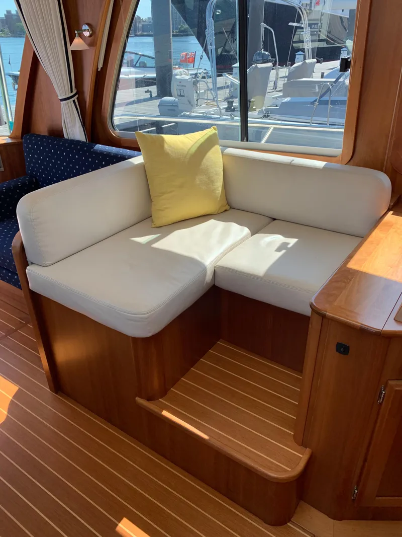 Slide: The Image of Interior of 2014 Sabre 48 Salon Express with white cushioned seating and yellow pillow. - 36