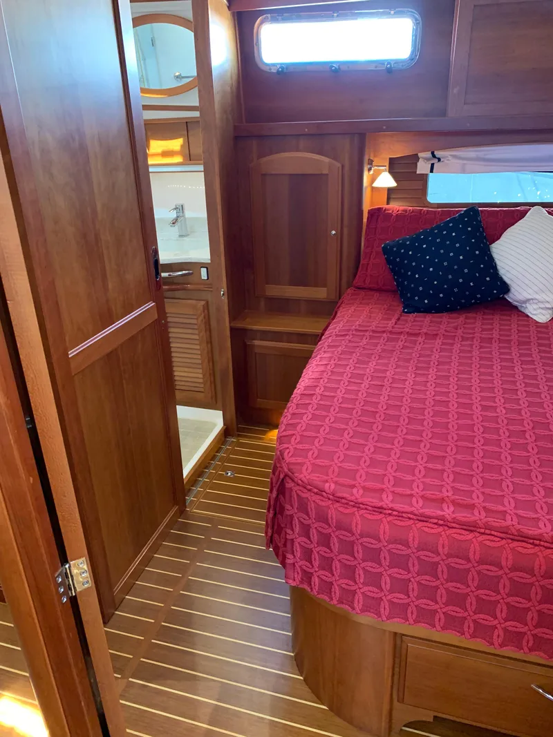 Slide: The Image of 2014 Sabre 48 Salon Express cabin with red bedding and wooden interior. - 8