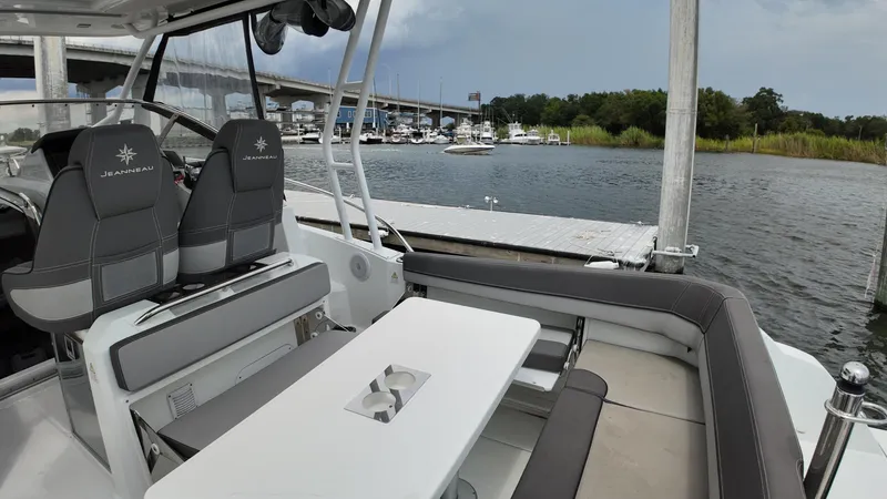 Slide: The Image of 2022 Jeanneau Leader 9.0 WA boat interior with seating and table, docked near a marina. - 25