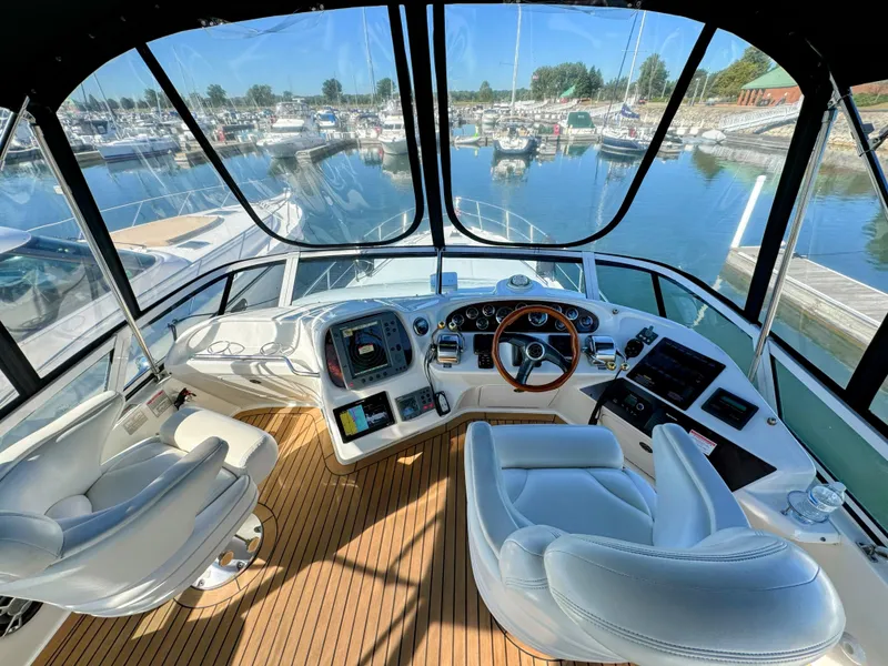 Slide: The Image of Interior view of 2001 Sea Ray 400 Sedan Bridge yacht cockpit with marina backdrop. - 8