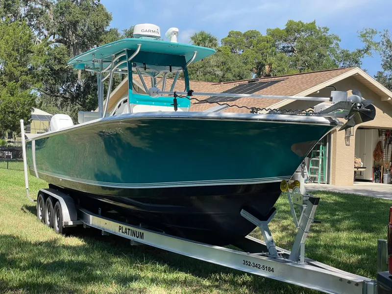 Slide: The Image of 2008 Palmetto 33 boat on trailer, parked in a grassy yard near a house. - 11