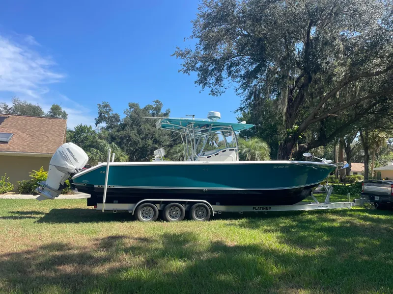 Slide: The Image of 2008 Palmetto 33 boat on trailer, parked on grass under trees. - 12
