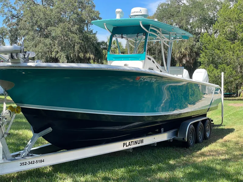Slide: The Image of 2008 Palmetto 33 boat on trailer, teal hull, parked on grass, surrounded by trees. - 13