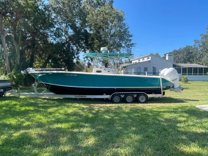 Slide: The Image of 2008 Palmetto 33 boat on trailer, parked on grass, with trees and house in background. - 14