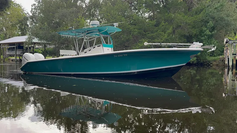 Slide: The Image of 2008 Palmetto 33 boat with teal hull, docked on calm water, surrounded by trees. - 7