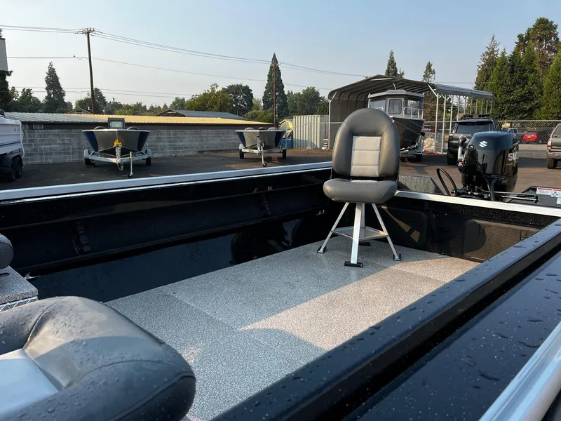 Slide: The Image of 2025 Fish Rite Angler 18 boat interior with seating and motor, parked outdoors. - 12