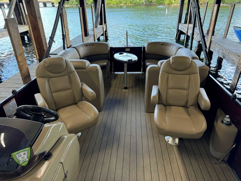 Slide: The Image of 2019 Starcraft SLS 3 boat interior with beige seating and table, docked by the water. - 3