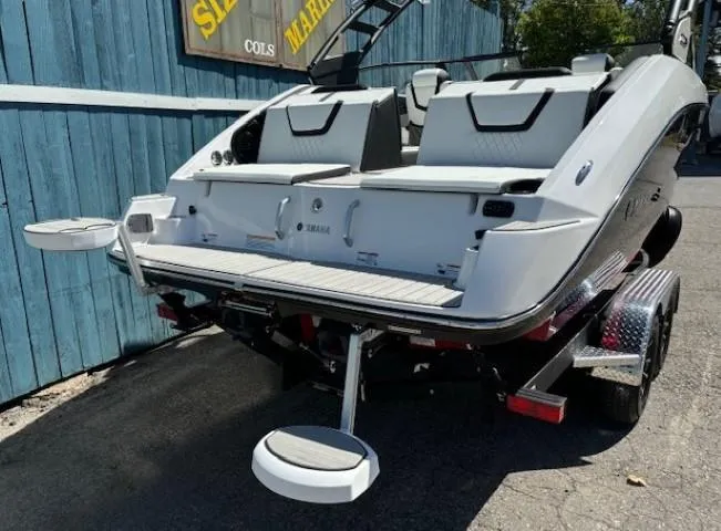 Slide: The Image of 2025 Yamaha Boats 222SD on trailer, rear view, white exterior, docked outdoors. - 5