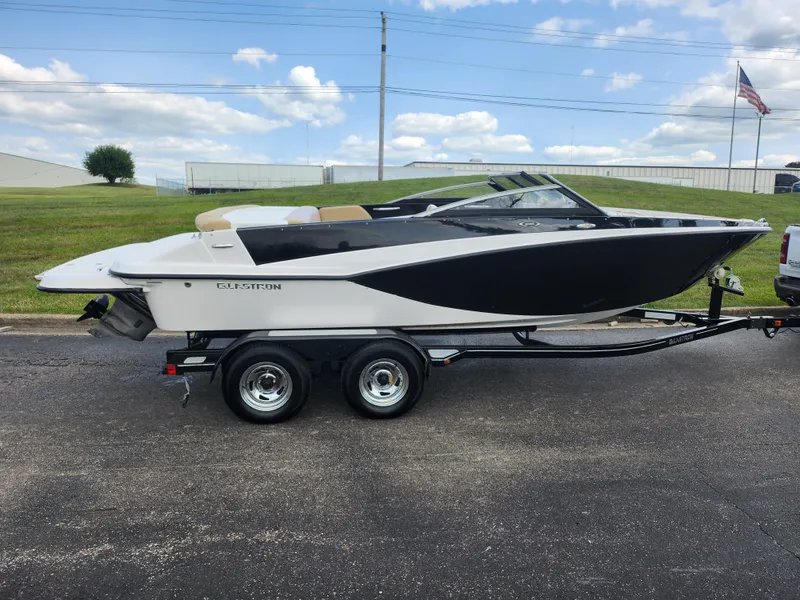 Slide: The Image of 2016 Glastron GT 205 boat on trailer, parked outdoors under a partly cloudy sky. - 4