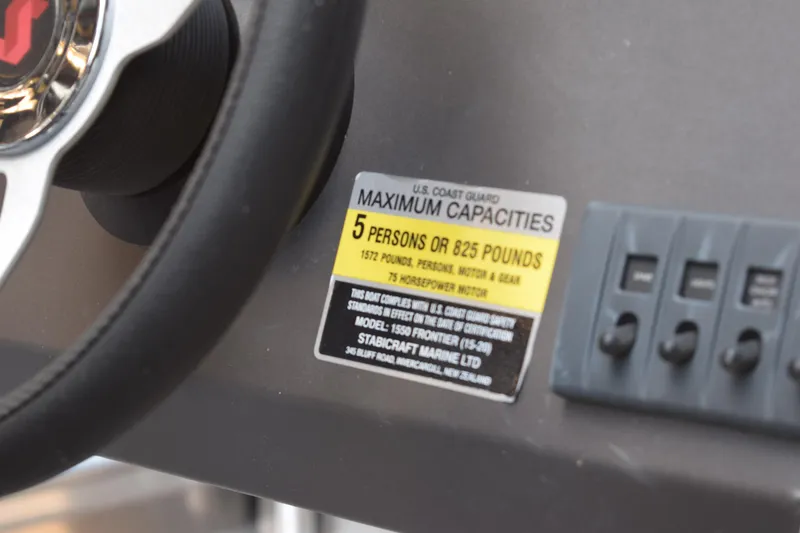 Slide: The Image of 2024 Stabicraft 1550 Frontier SportFish capacity label, steering wheel, and control switches. - 11