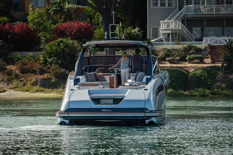 Slide: The Image of 2024 Riva 48 Dolceriva luxury yacht on serene water near a lush shoreline. - 12