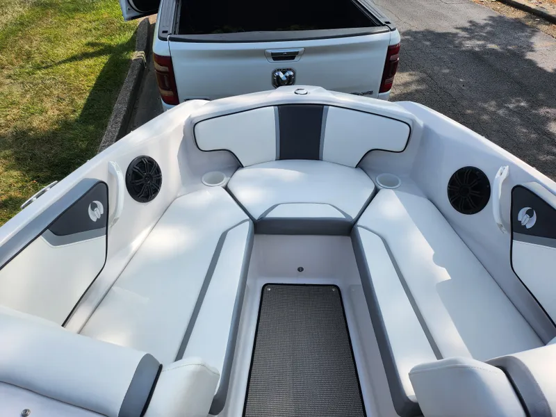 Slide: The Image of 2017 Scarab 195 boat interior with white and gray seating, parked near a white truck. - 17