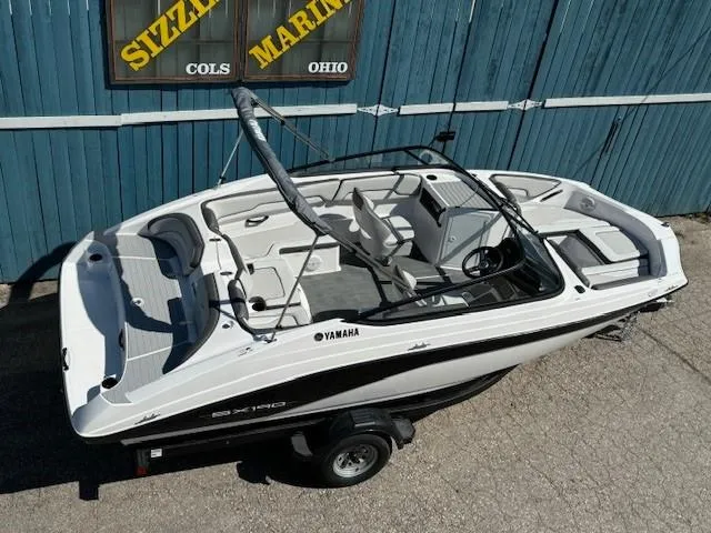 Slide: The Image of 2025 Yamaha SX190 boat on trailer, parked near blue building, Sizzle Marine sign visible. - 5