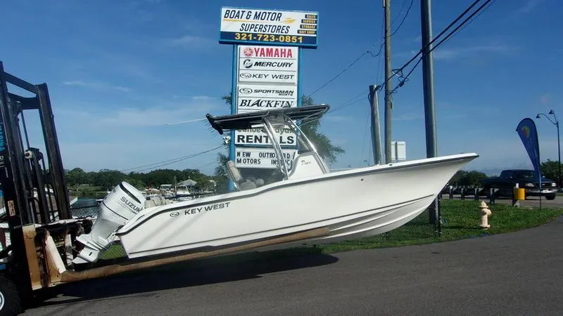 Slide: The Image of 2025 Key West 239 FS boat on forklift at dealership, with rental sign in background. - 1