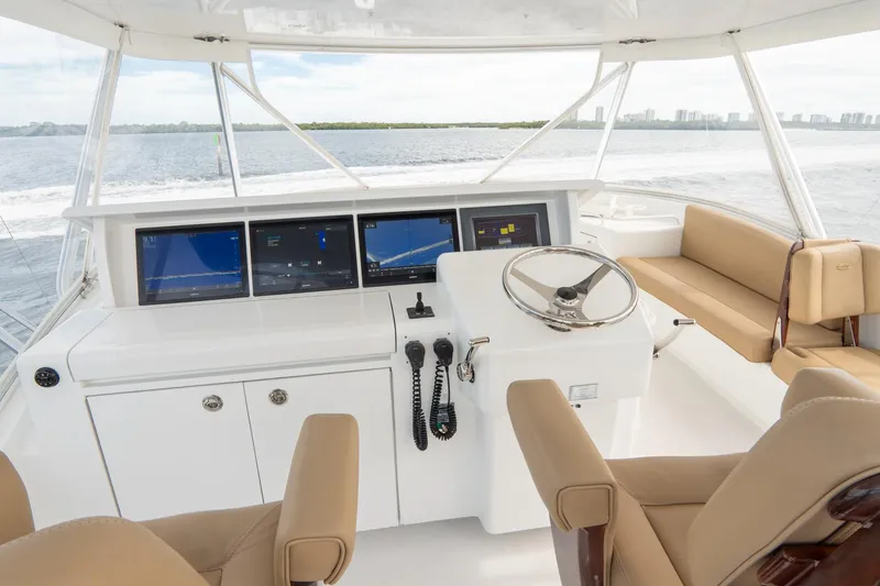 Slide: The Image of Hatteras GT60 2010 yacht helm with modern navigation displays and beige seating. - 20