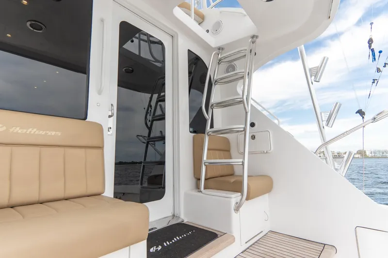 Slide: The Image of 2010 Hatteras GT60 yacht with beige seating and ladder, docked by the water. - 26