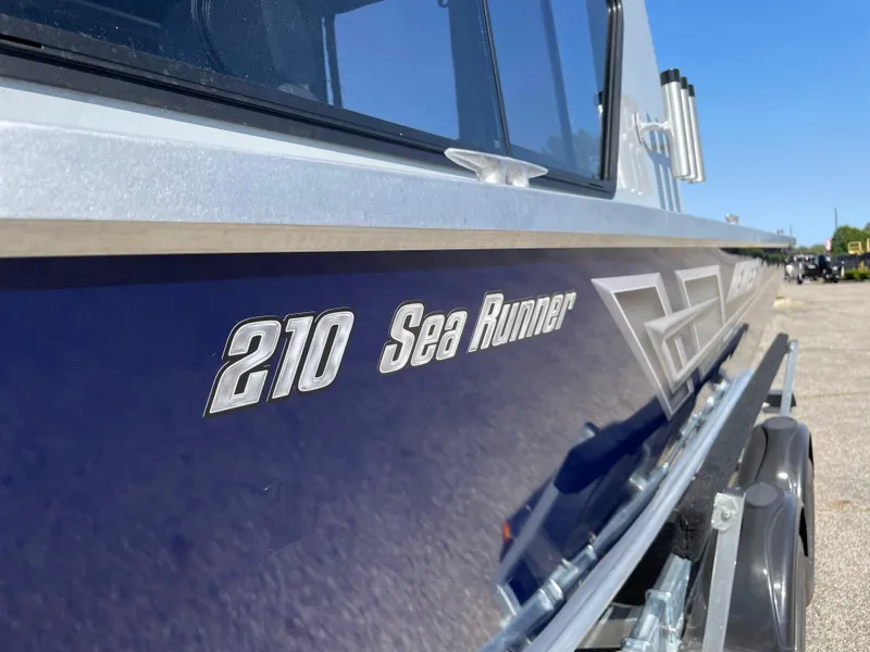 Slide: The Image of 2025 Hewescraft 210 Sea Runner ET HT boat, side view, blue exterior. - 26