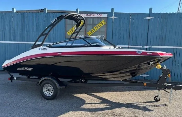 The Image of 2025 Yamaha AR195 boat on trailer, sleek black and red design, parked outdoors. - 0