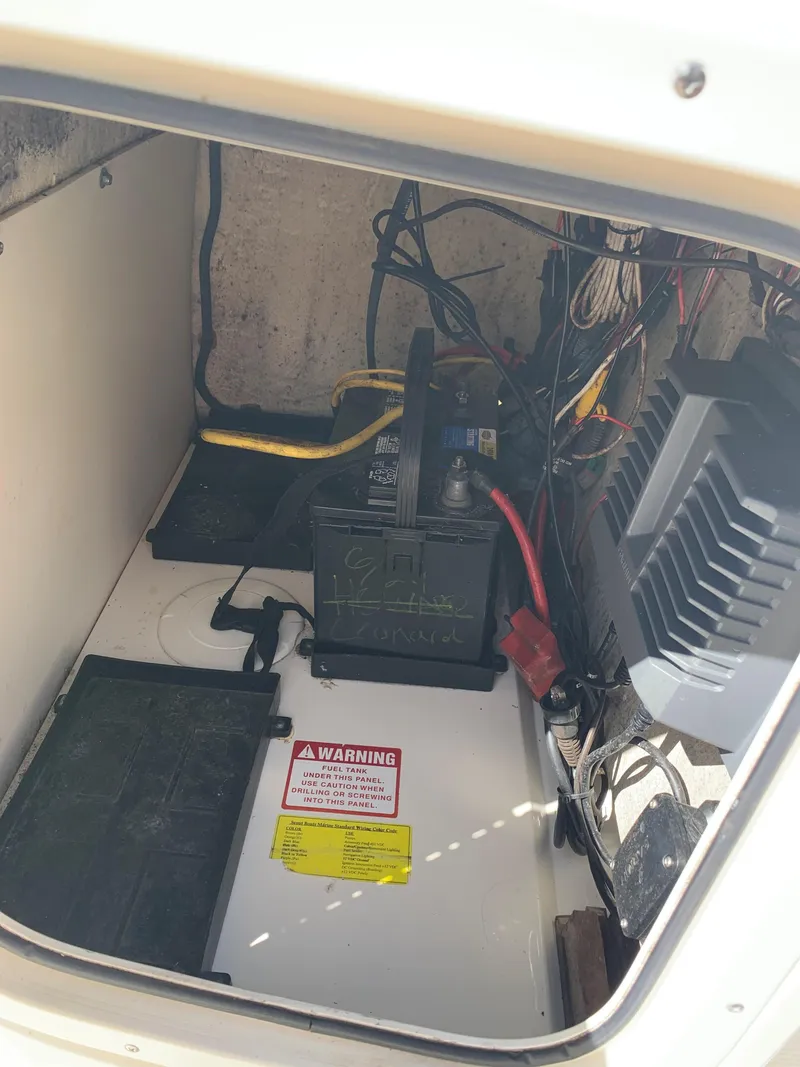 Slide: The Image of 2008 Scout 221 Winyah Bay boat battery compartment with wiring and warning label. - 10