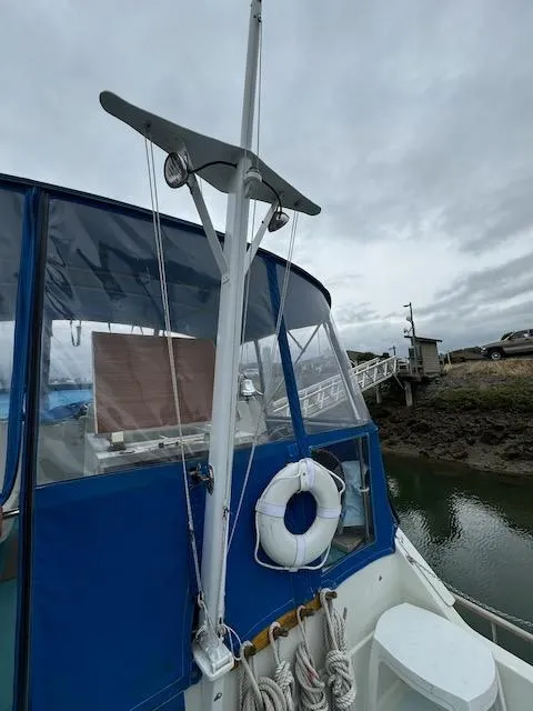 Slide: The Image of 1974 Tollycraft 40 Tri-Cabin boat with blue canopy and life preserver, docked by the shore. - 17